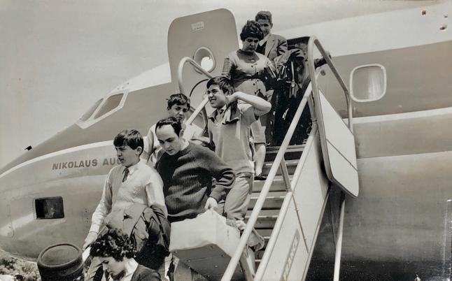 A group of people are exiting an aeroplane 
