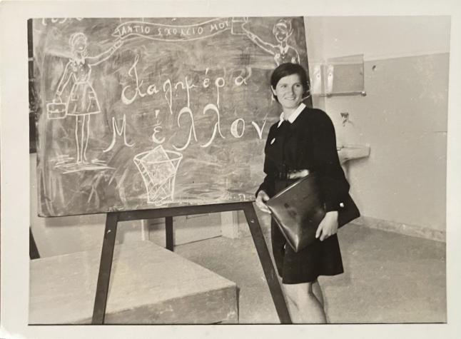 Woman holding a large bag standing in front of a chalk board 