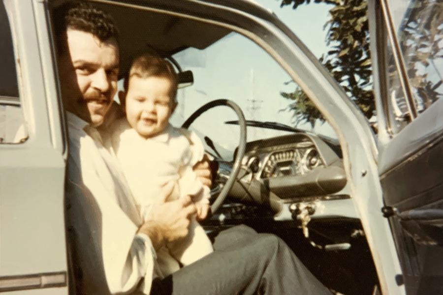 A person sitting in a vehicle holding a small child 