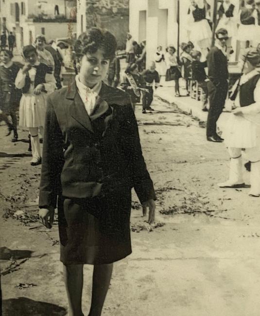 a black and white photo of a woman in a suit standing in a street