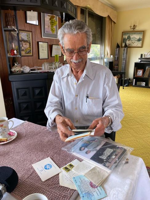 A man smiles while looking at old papers and photos