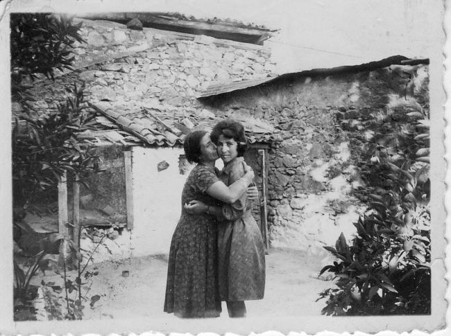 Two women hugging outside a house