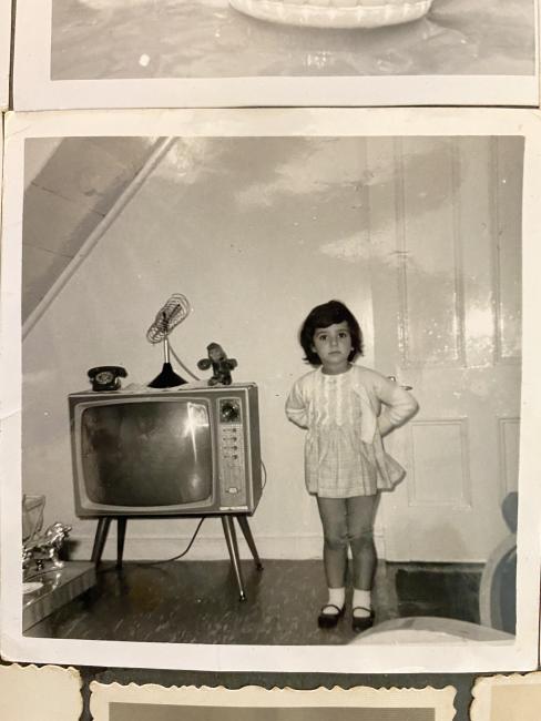 Child standing beside a television. 