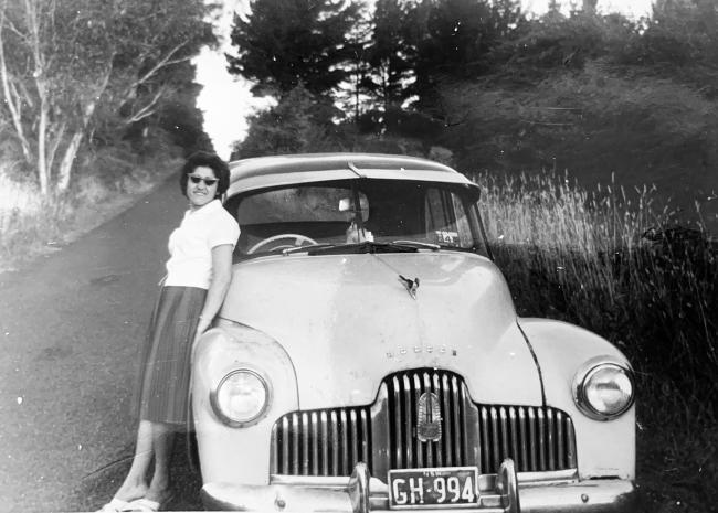 Woman leaning up against a car