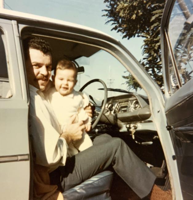 A person sitting in a vehicle holding a small child 