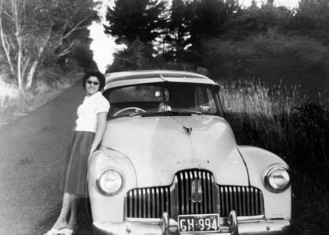 A person is leaning on the bonnet of a car